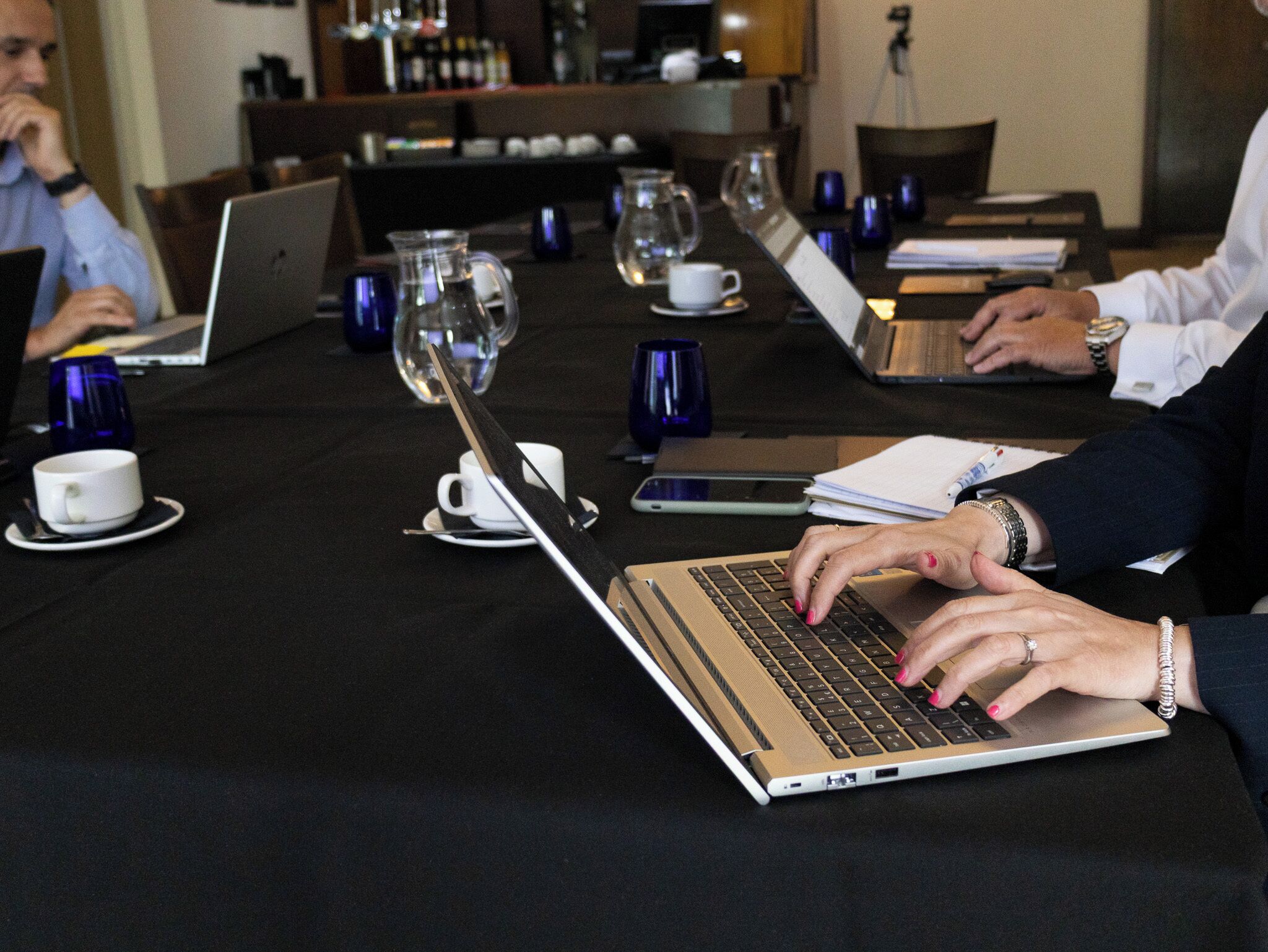 A conference table with laptops, notebooks, and coffee cups.