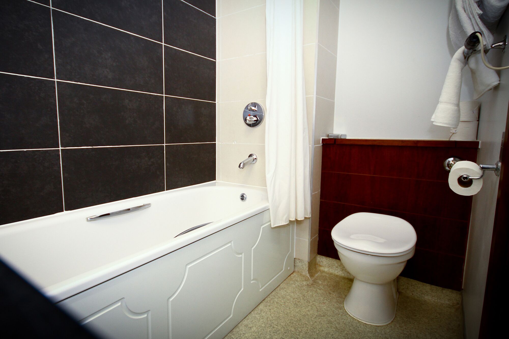 A bathroom with a bathtub, toilet, and a shower curtain.