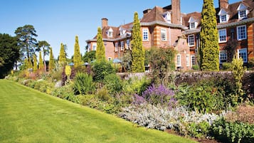 Un edificio grande e histórico con un jardín bien cuidado y un césped impecable.