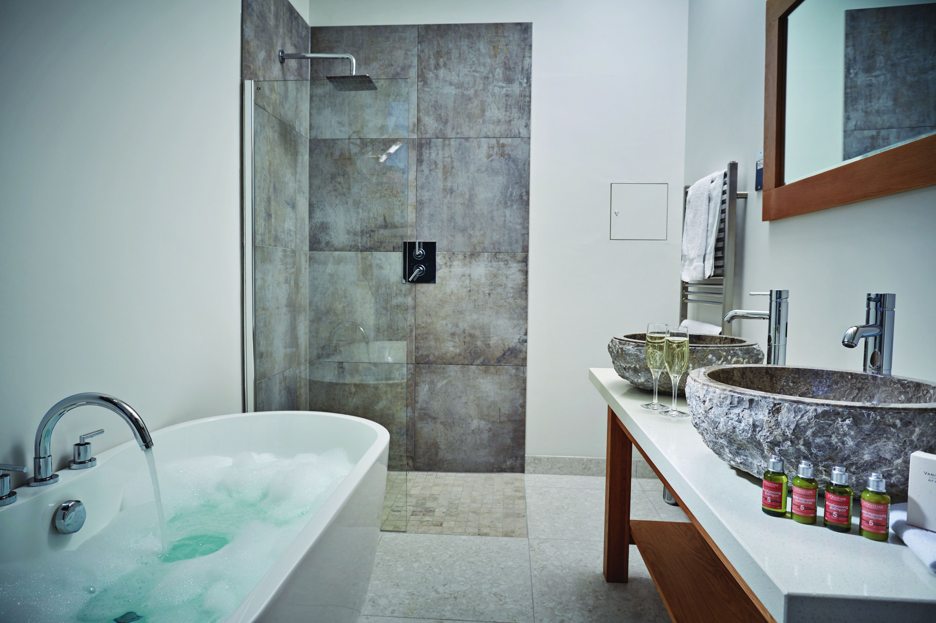 A modern bathroom with a freestanding bathtub, a large stone sink, and a glass-enclosed shower.