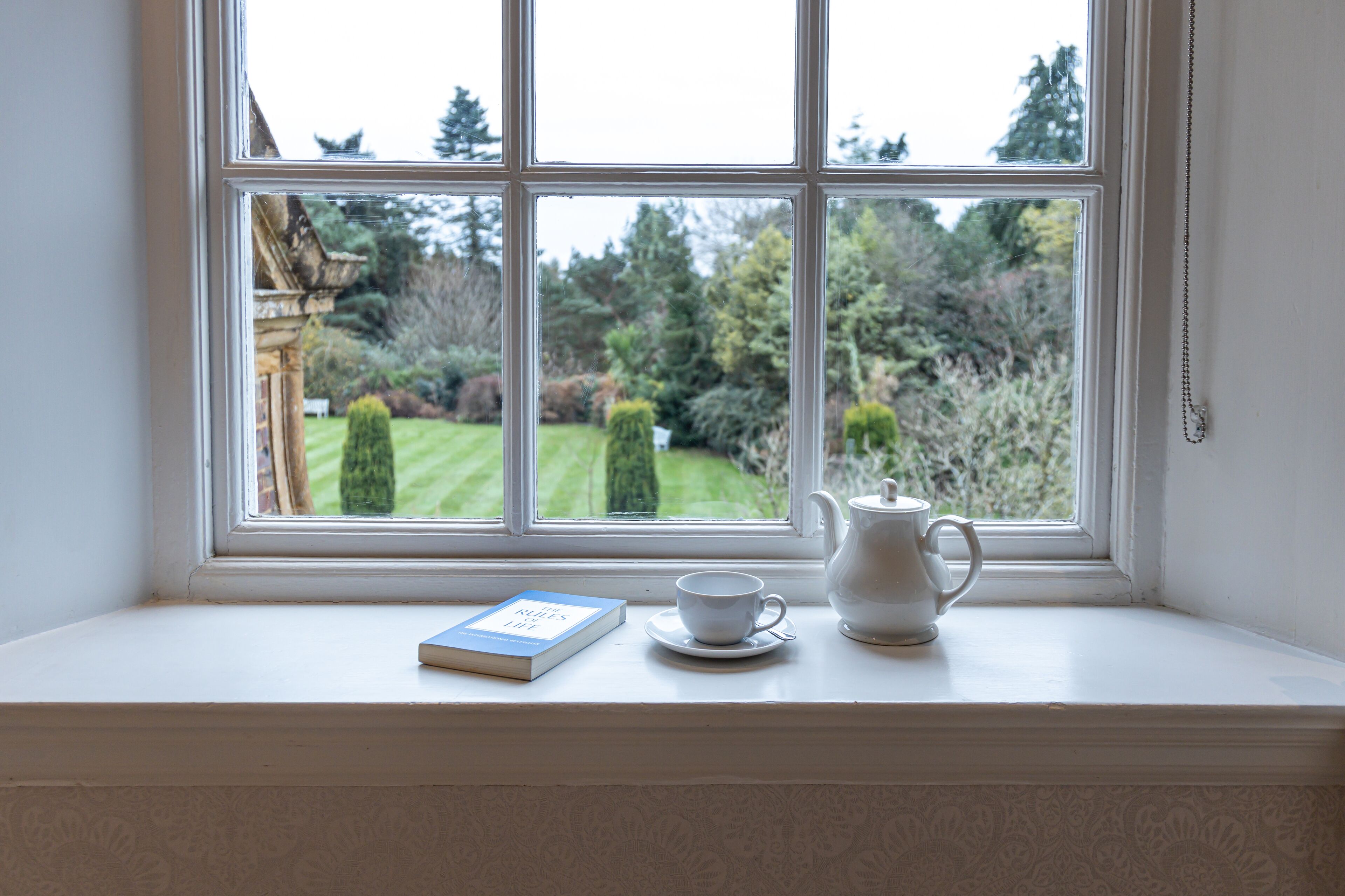 A window seat with a book, a cup, and a teapot.