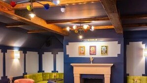A cozy lounge area with a blue sofa, a fireplace, and a wooden ceiling. - The Georgian, Haslemere, Surrey (Haslemere)