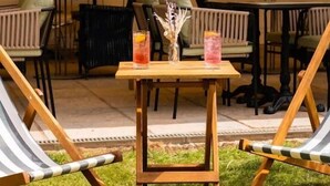 An outdoor seating area with two lounge chairs and a table, featuring drinks and a vase with flowers. - The Georgian, Haslemere, Surrey (Haslemere)