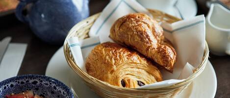 A breakfast setting with croissants, a bowl of fruit, and a teapot.