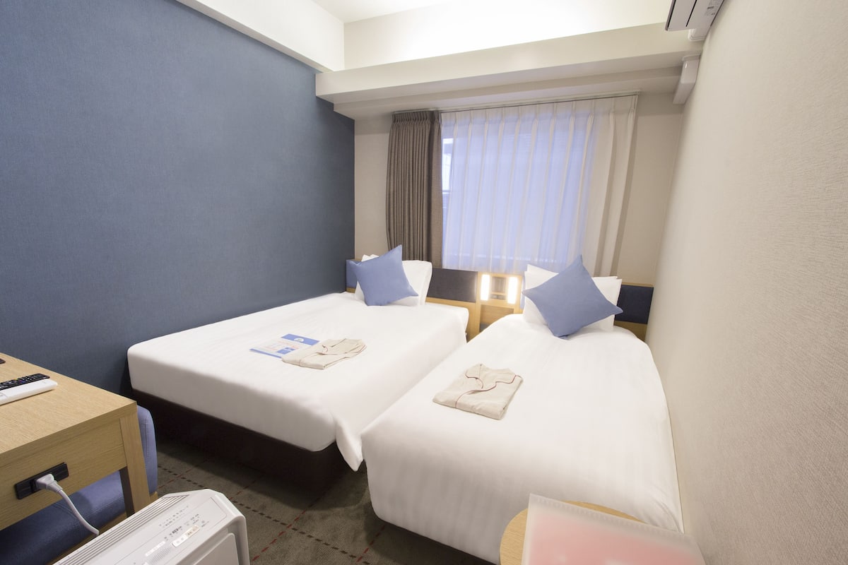 Une chambre d’hôtel avec deux lits, un bureau et une table de chevet.