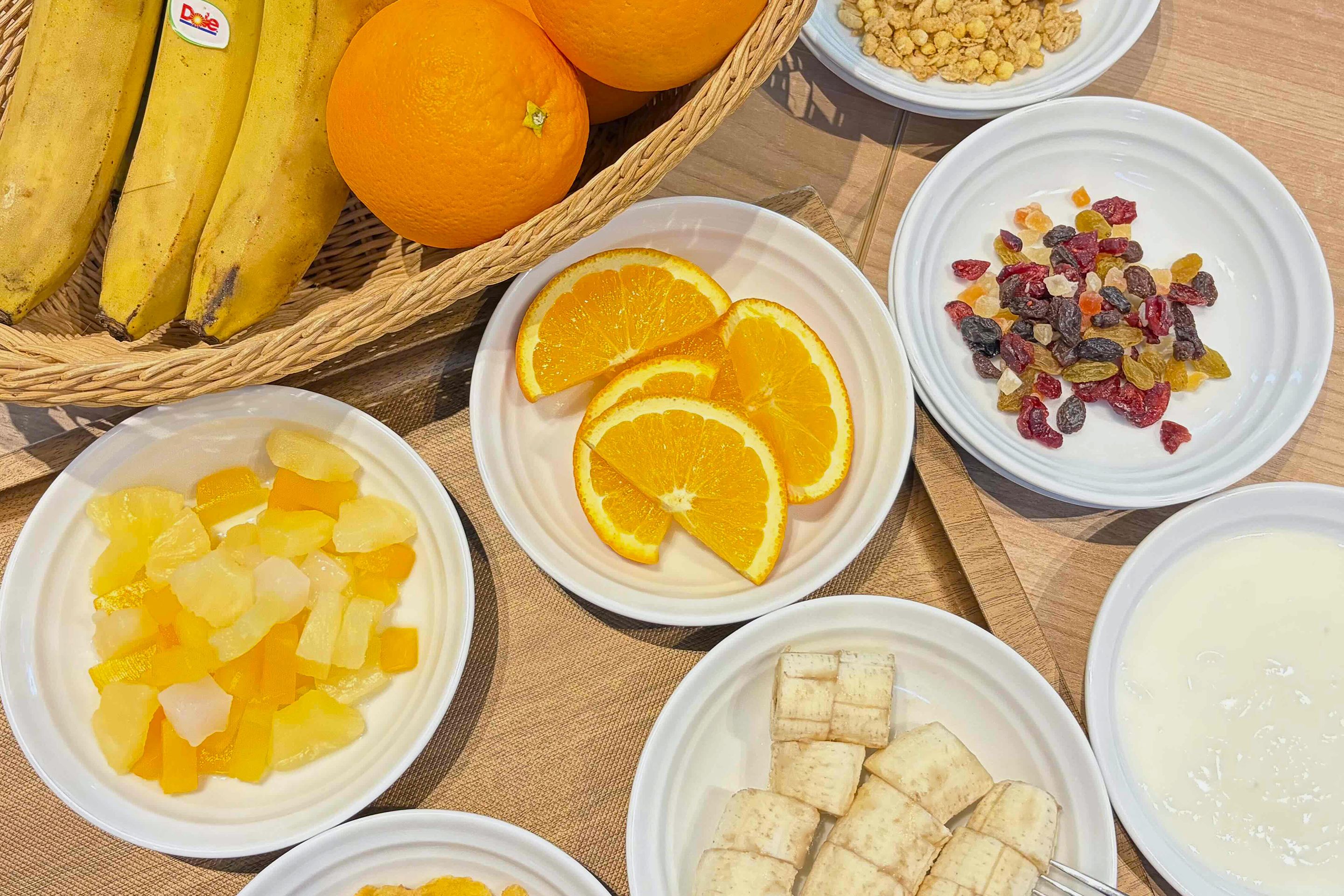 Una mesa con diversos alimentos, incluyendo frutas frescas, frutos secos y un plato que parece ser tofu.