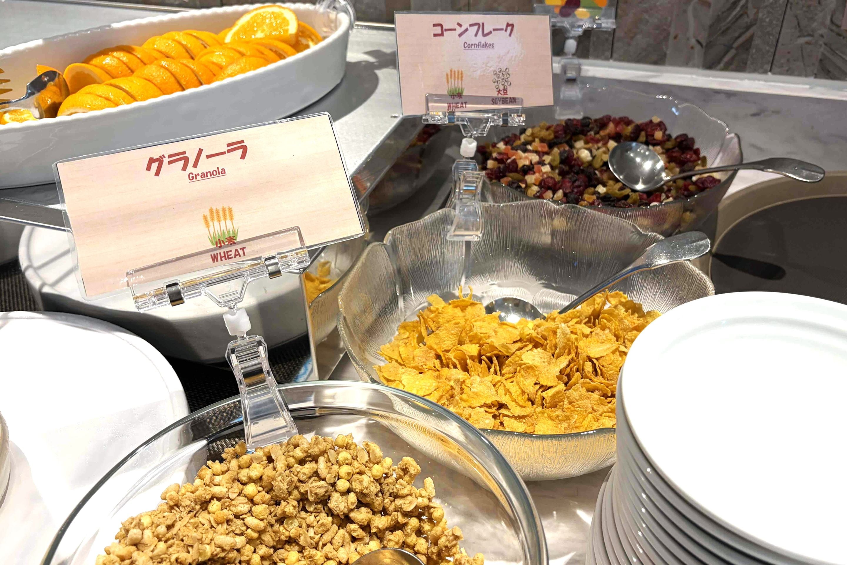 A buffet with various food options including granola, cornflakes, and cereal.