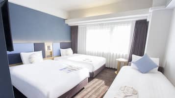 Een hotelkamer met twee bedden, een televisie, een raam met gordijnen en een klein tafeltje.
