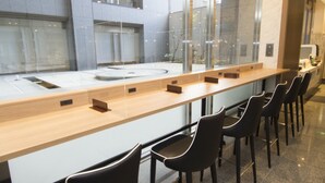 A modern bar area with a long counter and several black chairs.