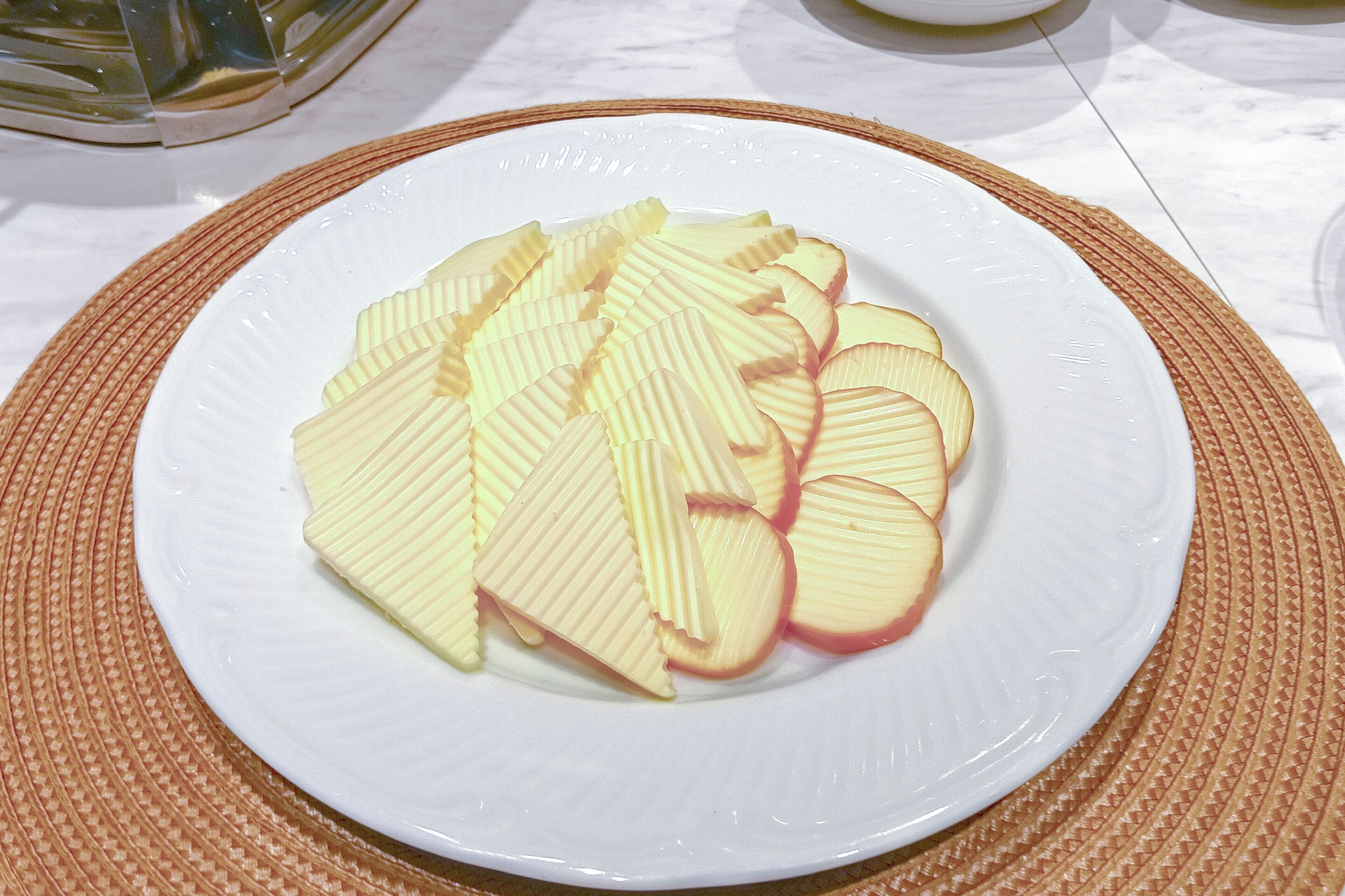 A white plate with sliced apples on a brown placemat.
