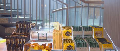 Exhibición de productos de té y café en una tienda, con una escalera y barandillas de vidrio al fondo.