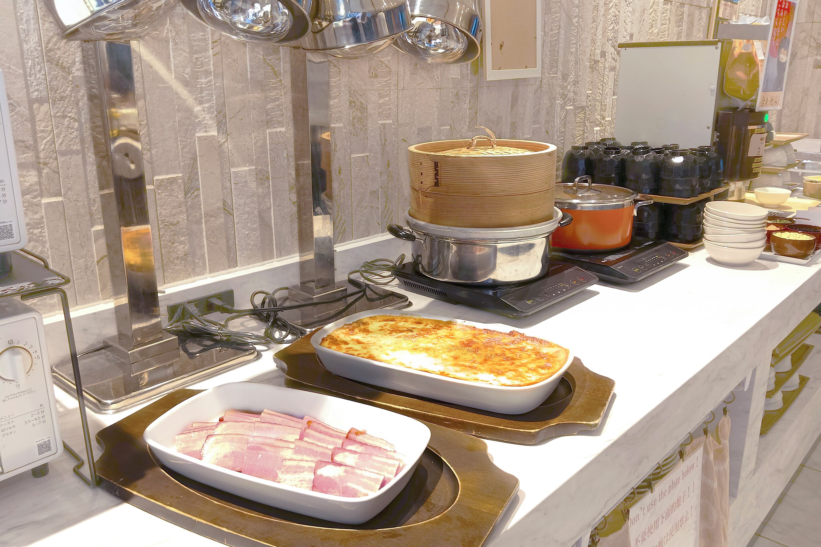 A buffet setup with various food items and cooking equipment.