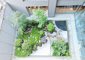 Un jardin sur le toit, agrémenté de diverses plantes, de rochers et d’un espace aménagé pour s’asseoir.