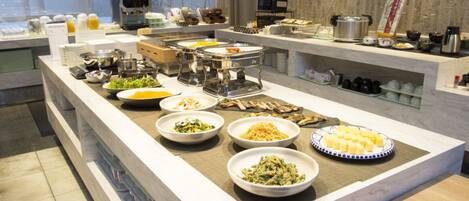 A buffet with various dishes and a coffee machine.
