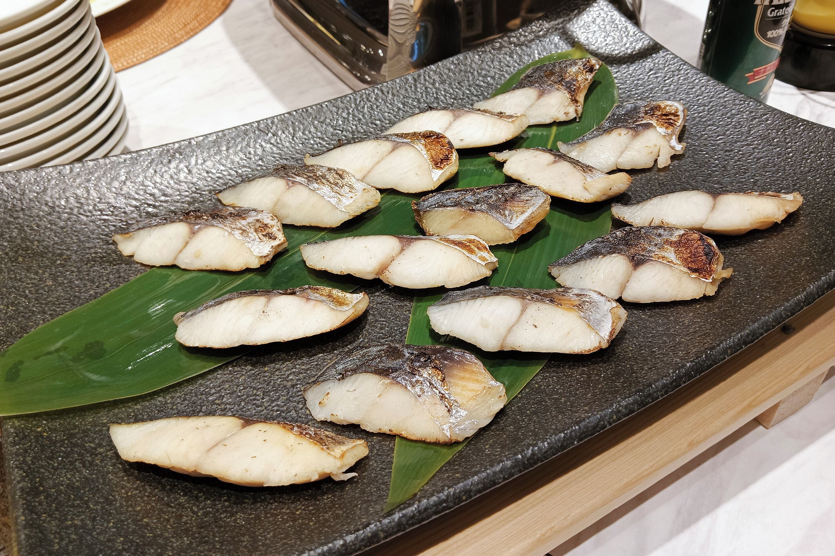 A table with grilled fish on banana leaves.