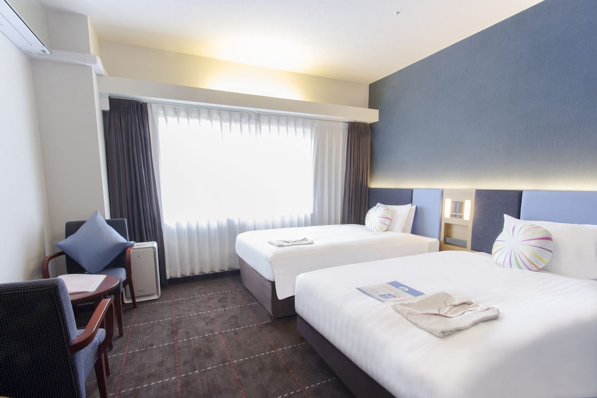 Une chambre d’hôtel avec deux lits, un bureau et une chaise.