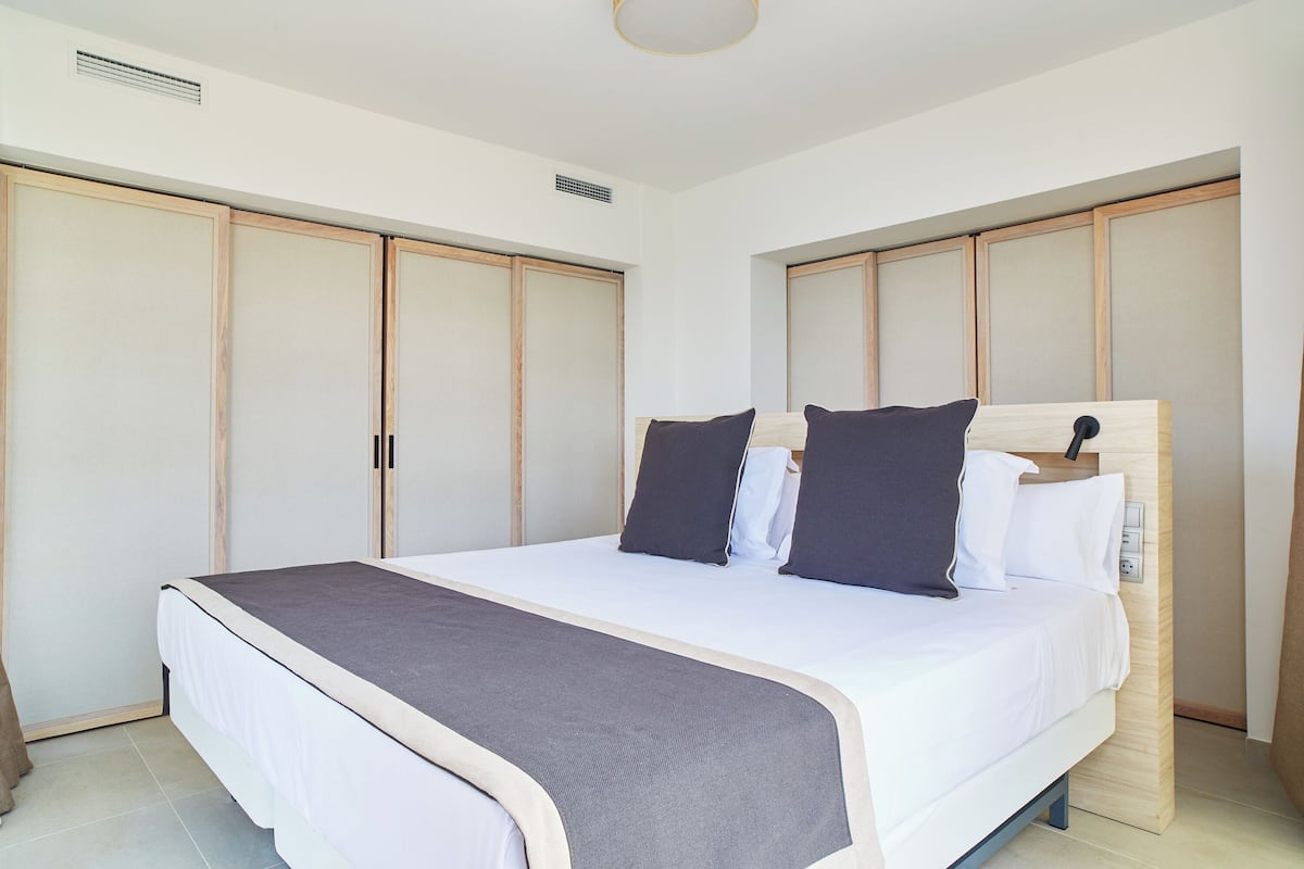 A bedroom with a bed, wooden wardrobe, and a bedside table.