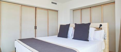 A bedroom with a bed, wooden wardrobe, and a bedside table.
