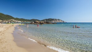 A beach with clear water, a sandy shore, and rocky hills in the background. - Invisa Hotel Club Cala Verde (Santa Eulalia del Rio)