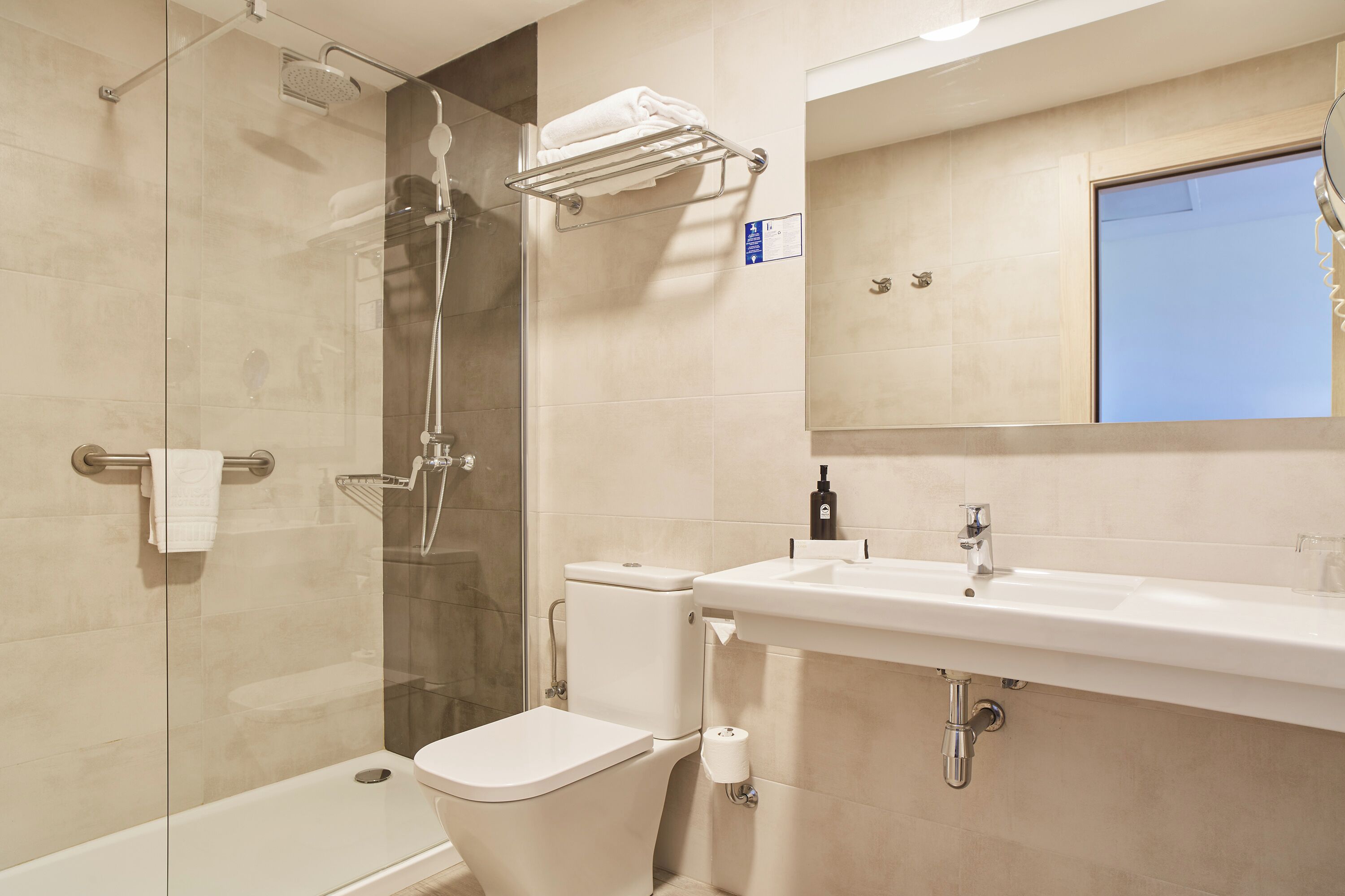 A modern bathroom with a glass-enclosed shower, a white toilet, and a sink with a mirror above it.