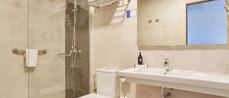 A modern bathroom with a glass-enclosed shower, a white toilet, and a sink with a mirror above it.