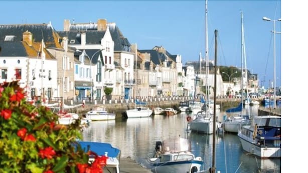Un port où des bateaux sont amarrés, des bâtiments aux styles architecturaux distincts et un ciel dégagé.