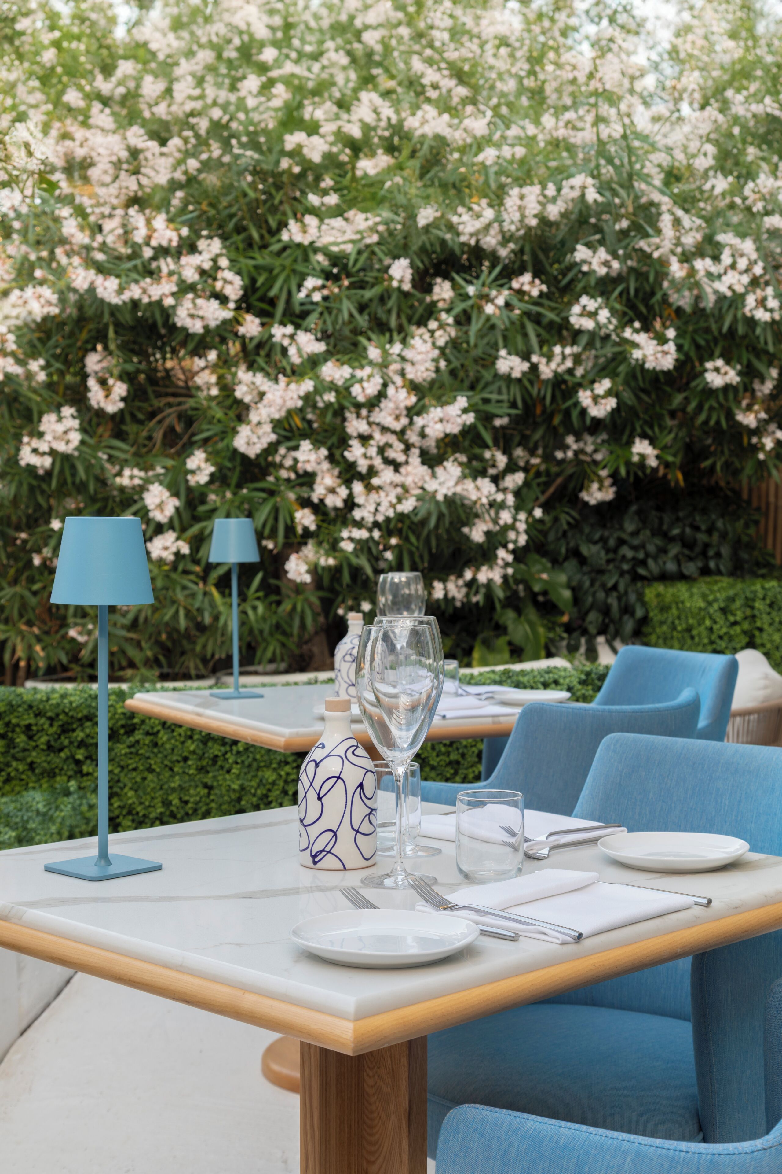 A table set outdoors with a view of blooming flowers and greenery.
