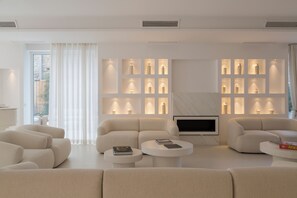 Un soggiorno moderno con un divano componibile, due tavolini, una televisione a schermo piatto e una parete con illuminazione a incasso.