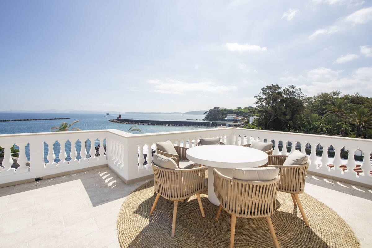 A terrace with wicker furniture and a view of the sea.