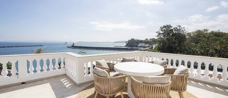 A terrace with wicker furniture and a view of the sea.