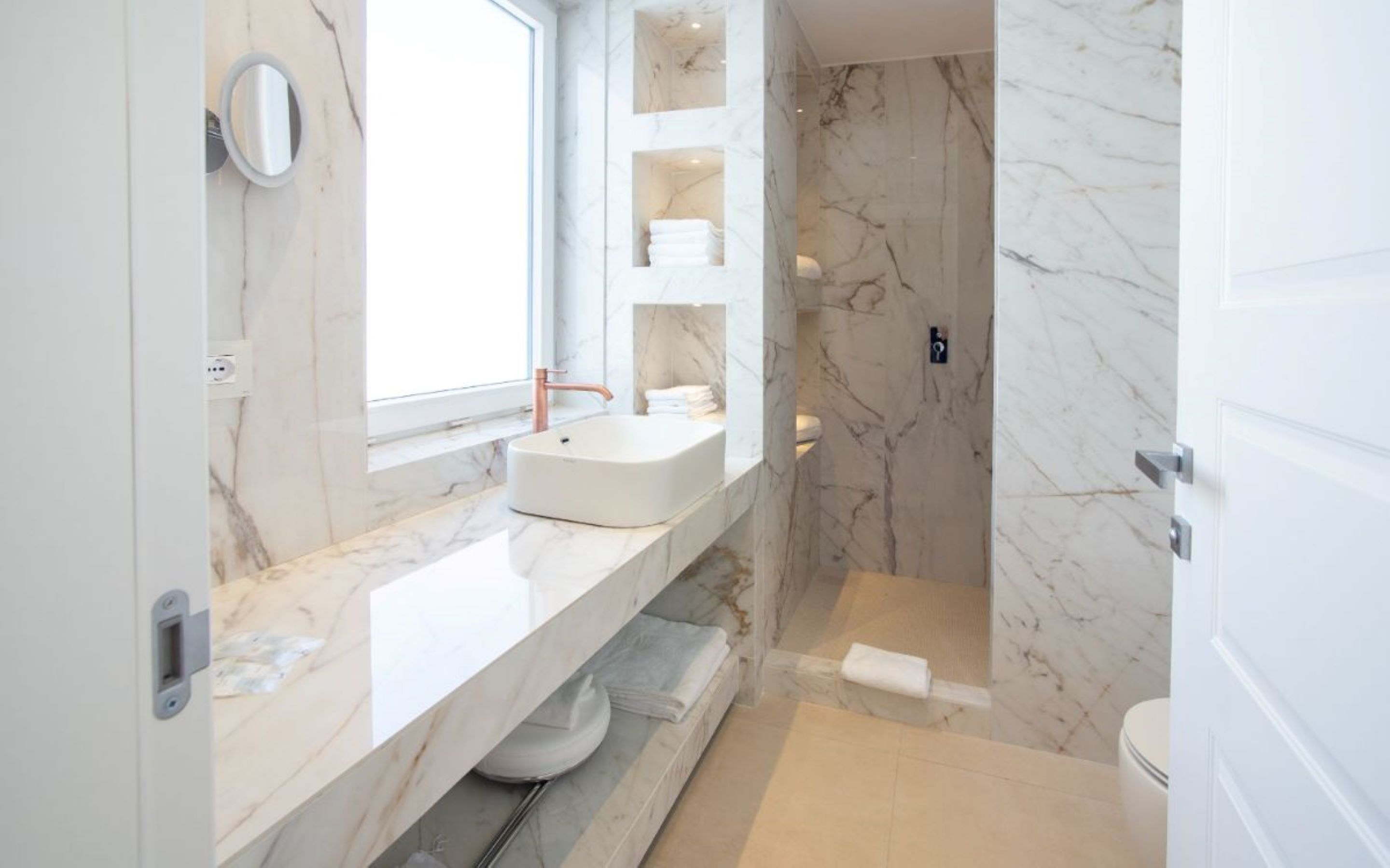 Ein modernes Badezimmer mit Waschtisch aus Marmor, einer freistehenden Badewanne und einer Duschkabine.