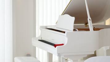 A modern living room with a white grand piano, a white sofa, and a small white table with a book and a picture frame.