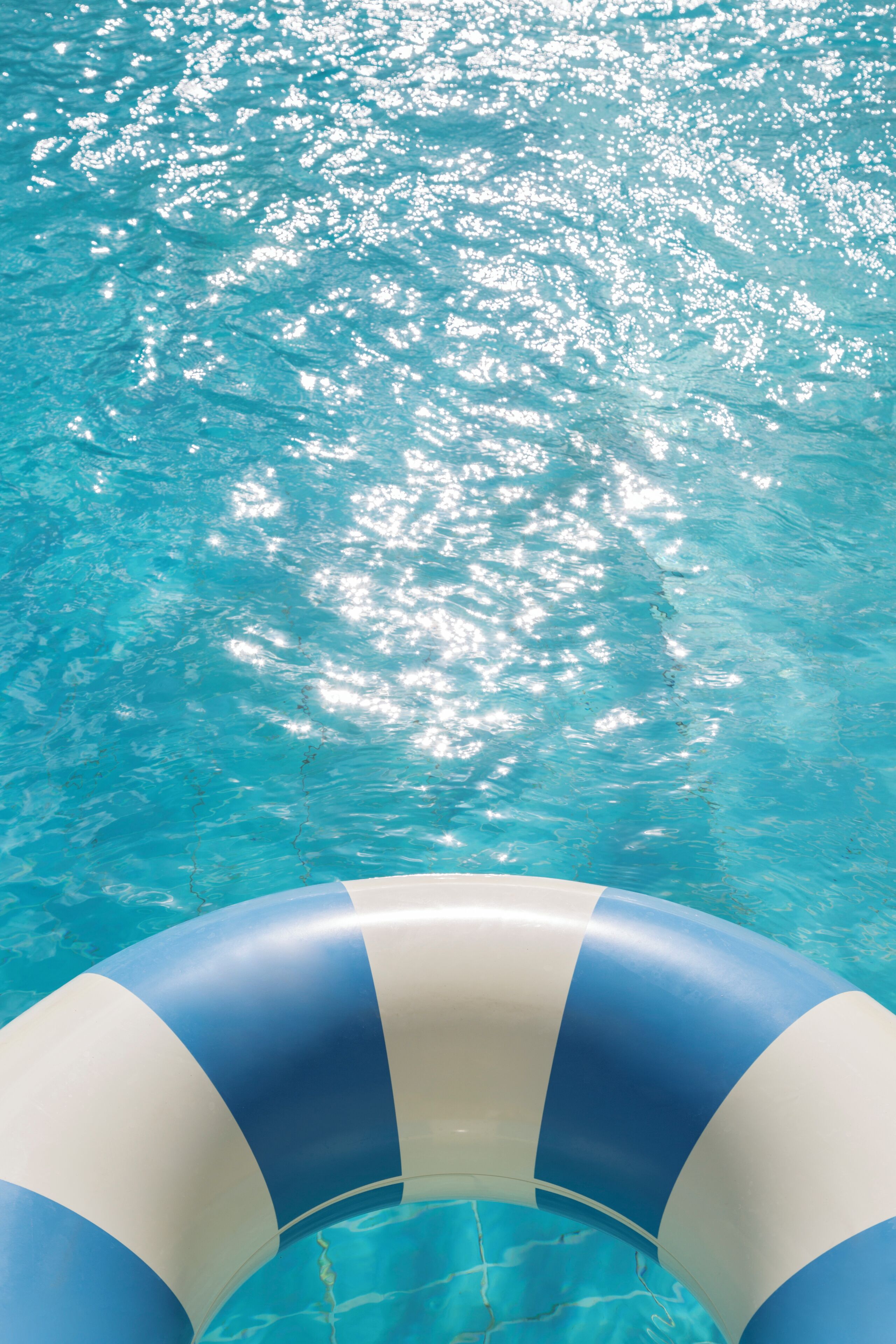 Una vista despejada de una piscina con un flotador inflable azul y blanco al frente.