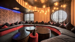 A modern lounge area with a curved seating arrangement, ambient lighting, and a patterned wall. - Rija VEF Hotel (Riga)