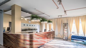 A reception area with a marble counter, a blue sofa, and a glass coffee table. - Rija VEF Hotel (Riga)