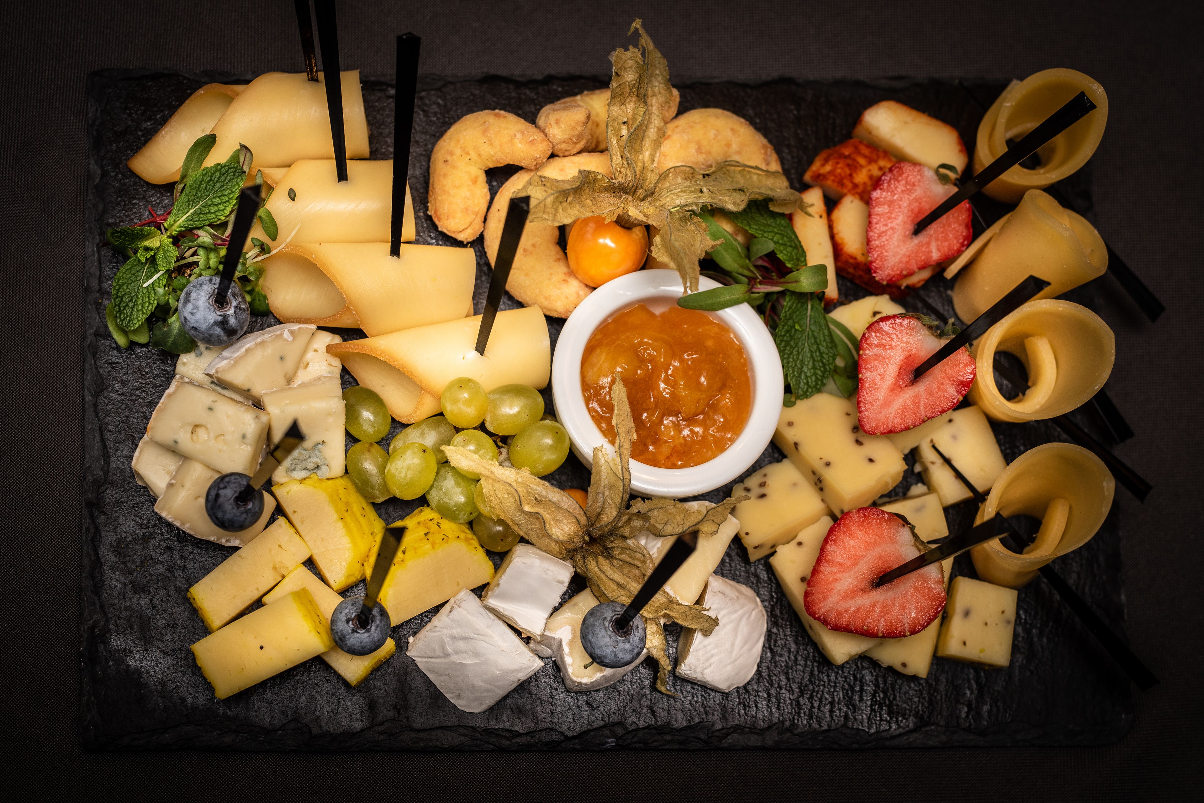 Una tabla de embutidos con varios quesos, frutas y frutos secos.