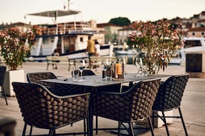 An outdoor dining area with a table set for two, surrounded by chairs with a textured pattern.