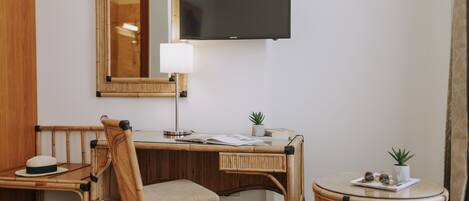 Une chambre d’hôtel avec un bureau en bois, une chaise, une table ronde, un téléviseur et un miroir.