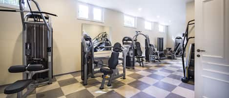 A gym with various exercise machines, a bench, and a mirror on the wall.