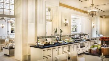 A buffet with various food items, a seating area with chairs, and a chandelier.