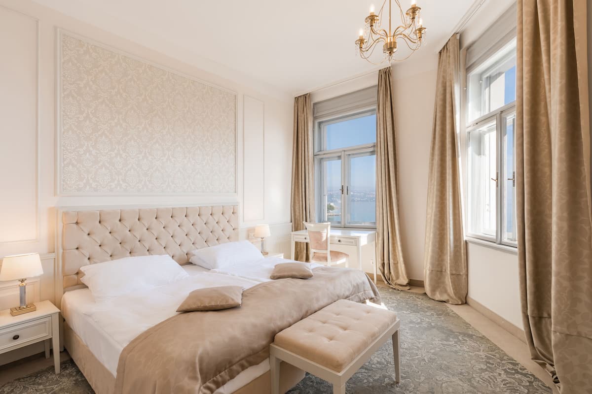 Ein geräumiges Schlafzimmer mit einem großen Bett, einem Schreibtisch und Blick auf die Stadt durch das Fenster.