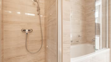 Un baño moderno con ducha de vidrio, bañera independiente y piso de baldosas.