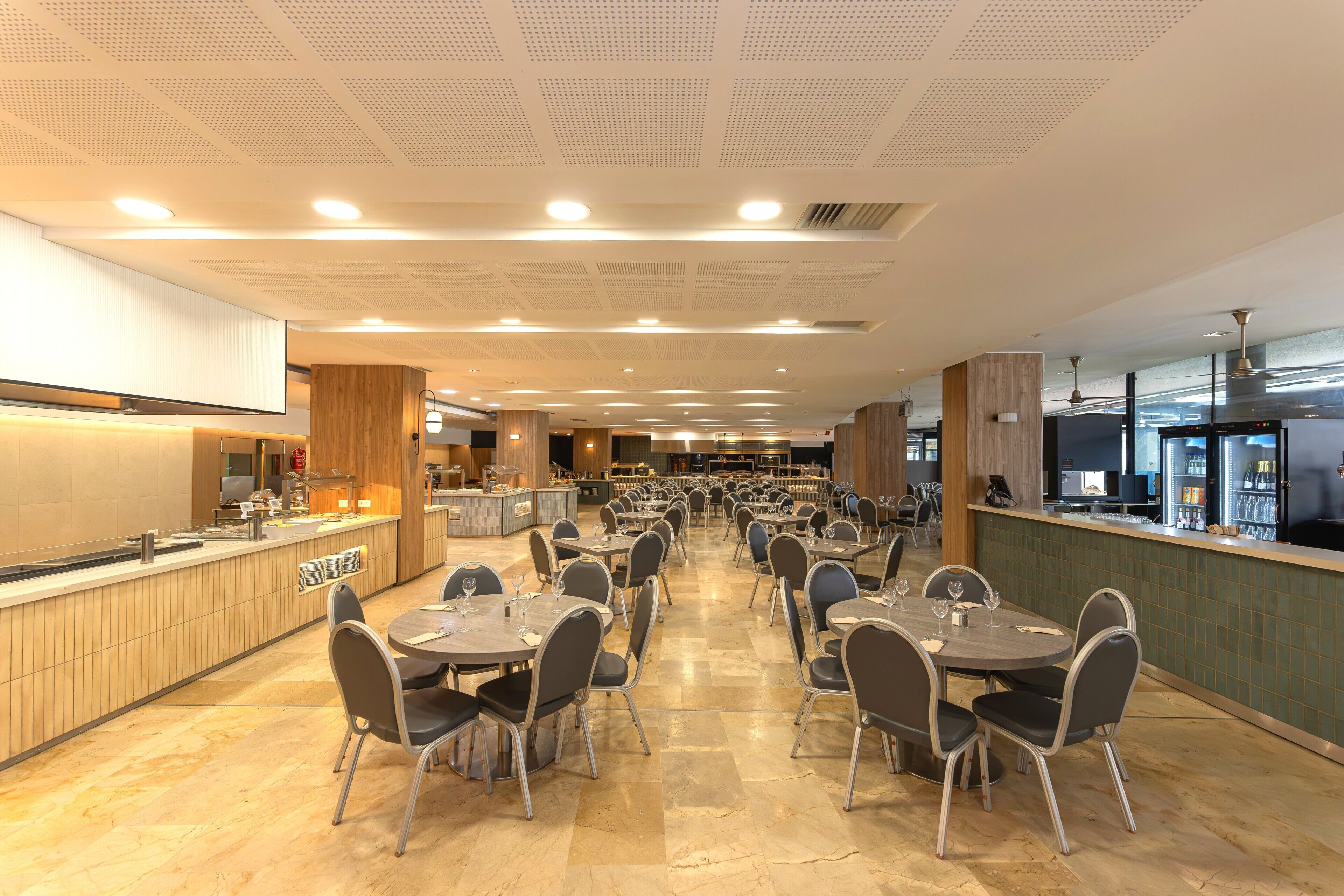 Un restaurante espacioso con varias mesas y sillas, una zona de cocina y una barra.