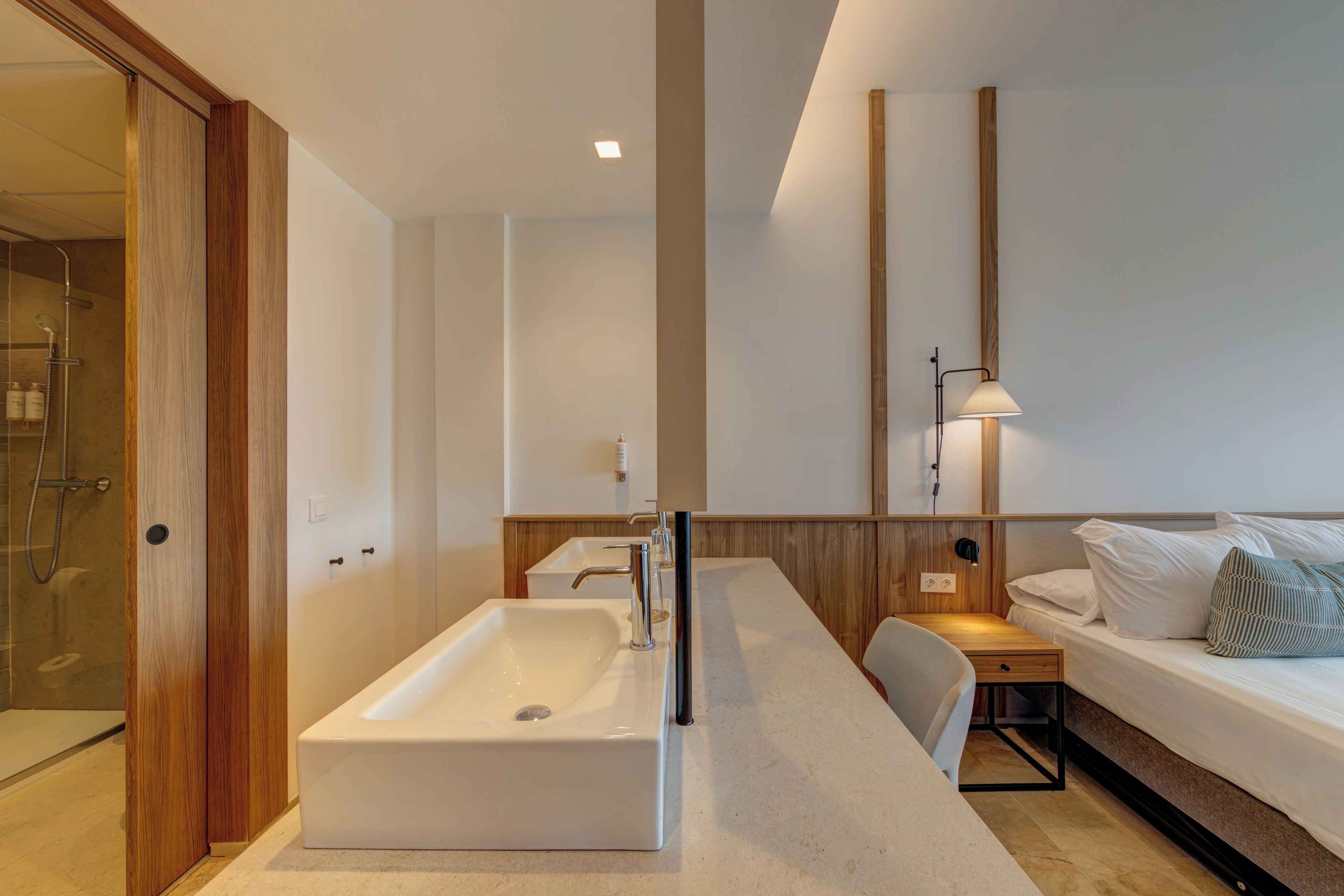 Ein modernes Badezimmer mit einem großen Waschbecken, einer Dusche und einem Nachttisch mit einer Lampe.