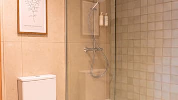 Un baño moderno con ducha de vidrio, inodoro blanco e ilustración botánica enmarcada en la pared.