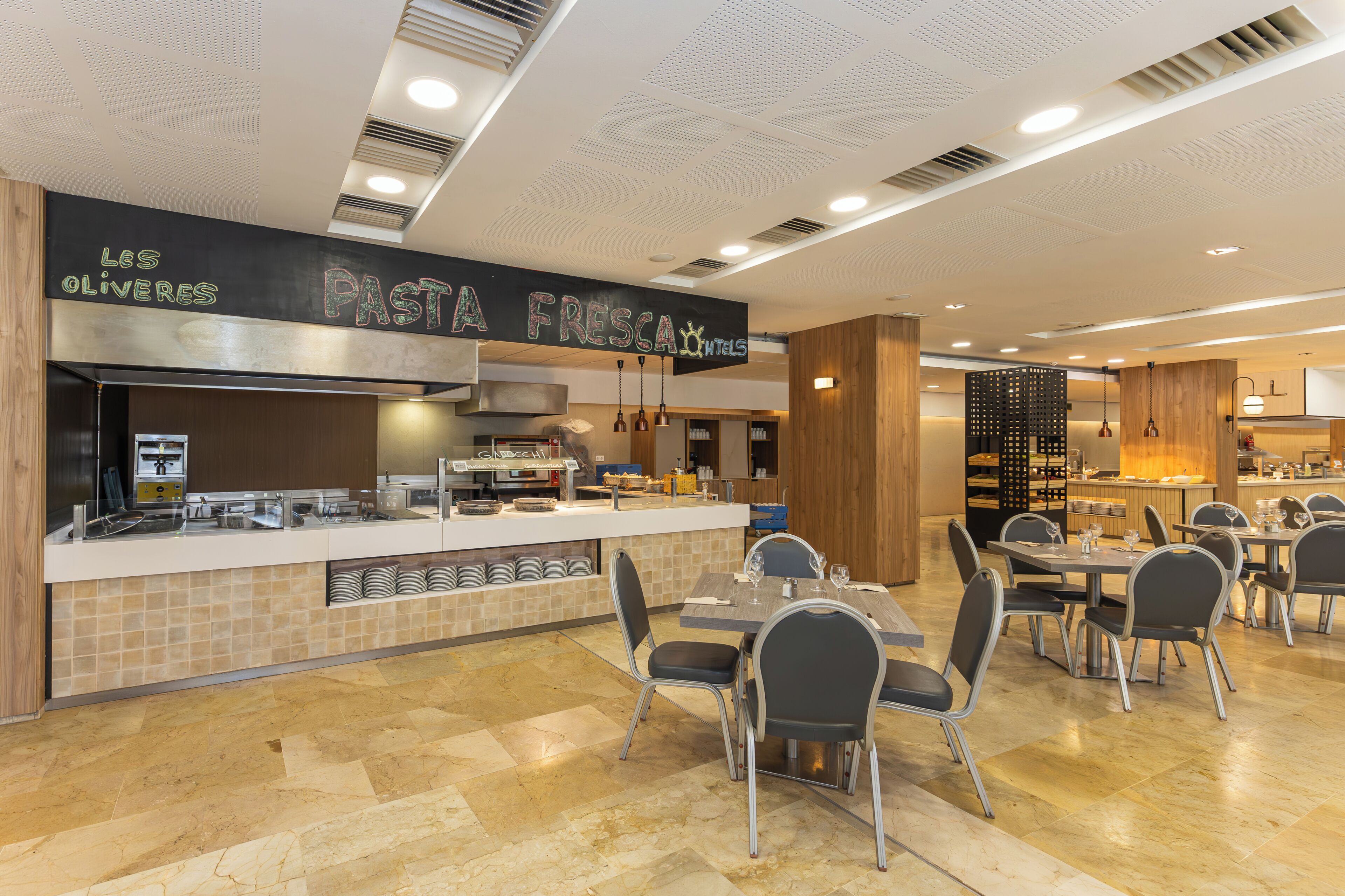 A modern restaurant with a chalkboard menu, a self-service counter, and a dining area with tables and chairs.