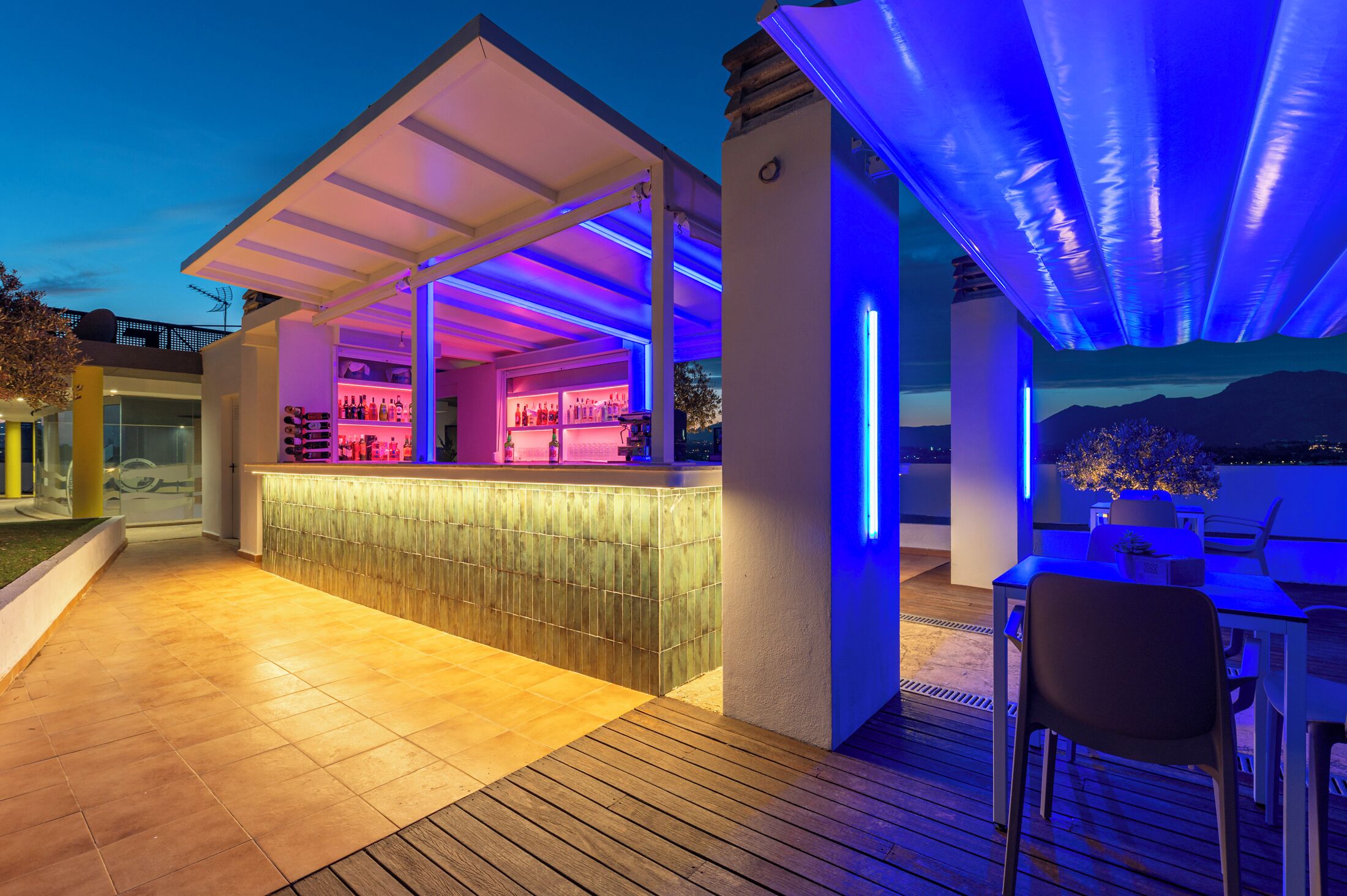 An outdoor bar area with a covered seating area and a poolside view.