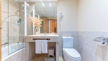 A modern bathroom with a glass-enclosed shower, a vanity with a mirror, a toilet, and a hairdryer mounted on the wall.
