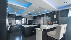 A modern kitchen with dark cabinetry, a central island, and a bar area with stools. - Karon Sea Sands Resort (Karon)