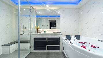 A modern bathroom with a glass-enclosed shower, a freestanding bathtub with rose petals, and a vanity with a mirror and sink.